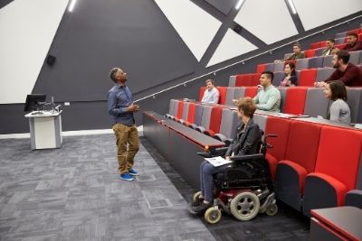 Étudiants dans un amphithéâtre incluant une élève en chaise roulante 