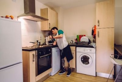 A man with prosthetic legs cooking in a kitchen