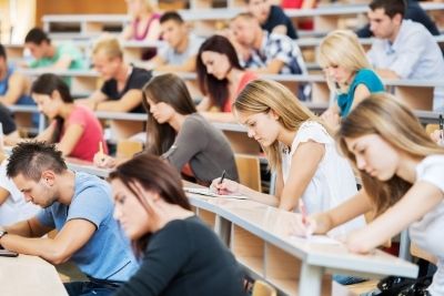 A variety of students sitting and taking notes in an auditorium.