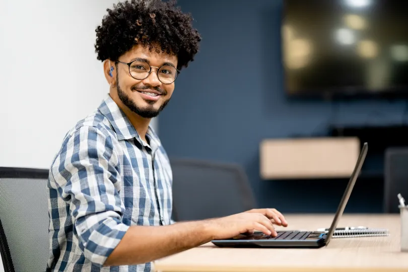 Portrait of a hearing impaired man with beard and curly hair working on laptop at office