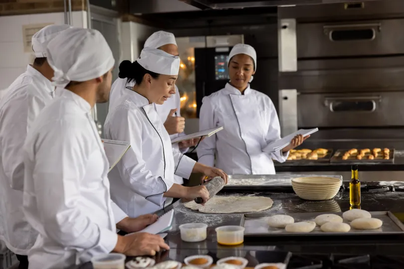 female chef in a cooking class teaching her students how to make bread