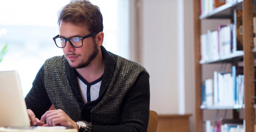 Young male student reading on a laptop