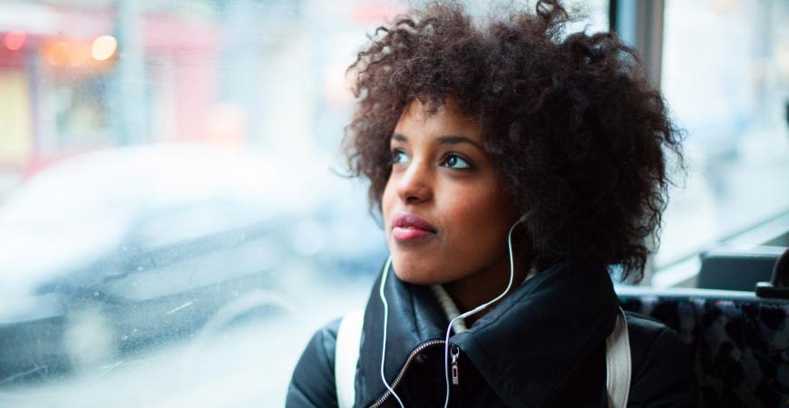 Woman on a bus staring out of the window with a pensive look