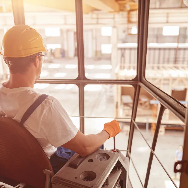 Back view of young man wearing safety construction helmet while operating industrial crane