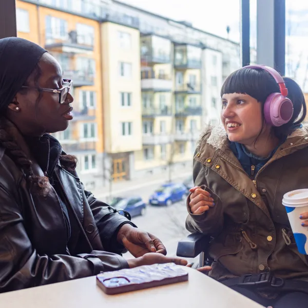 Joyful moment between neurodivergent teenage girl and personal care assistant at café