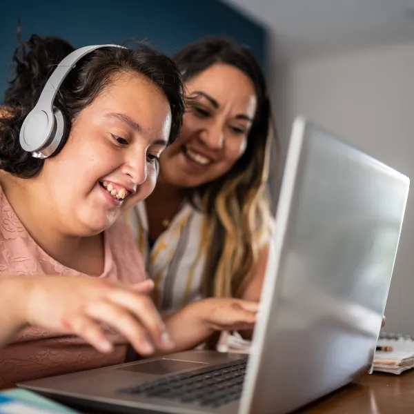 Mother helping daughter using laptop at home