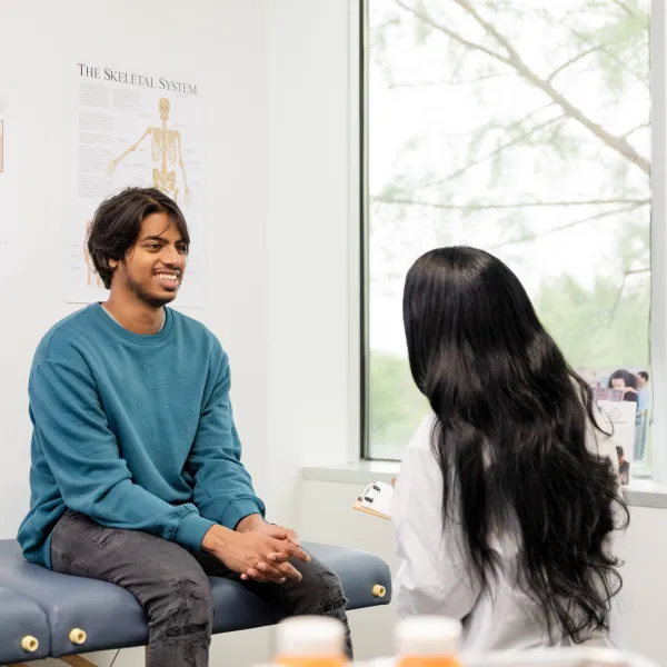 Young adult male smiles while speaking with a healthcare worker in a medical office