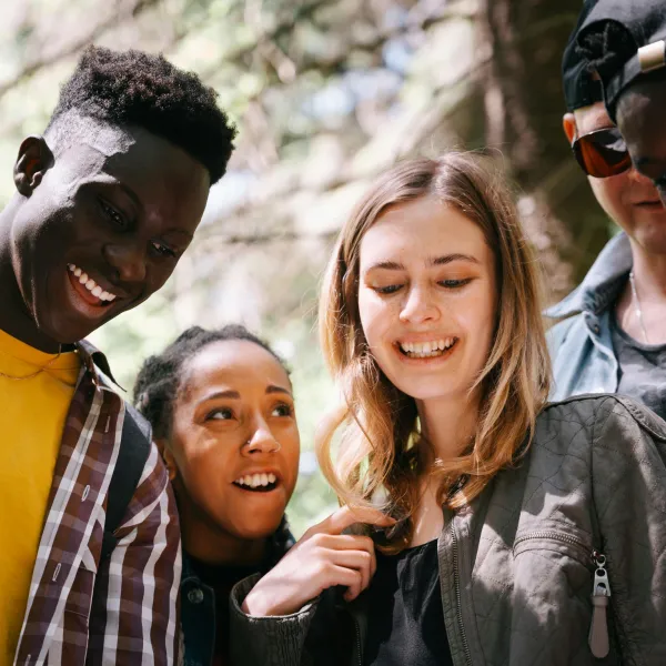 A group of diverse young adults enjoying a moment together outdoors, smiling and happy.