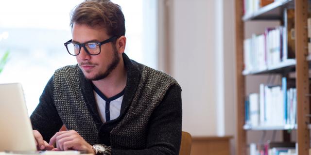 Young male student reading on a laptop