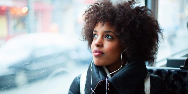 Woman on a bus staring out of the window with a pensive look