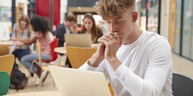 Homme dans la bibliothèque avec son ordinateur portable